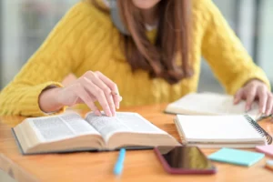 aluna estudando com caderno e materiais sobre a mesa